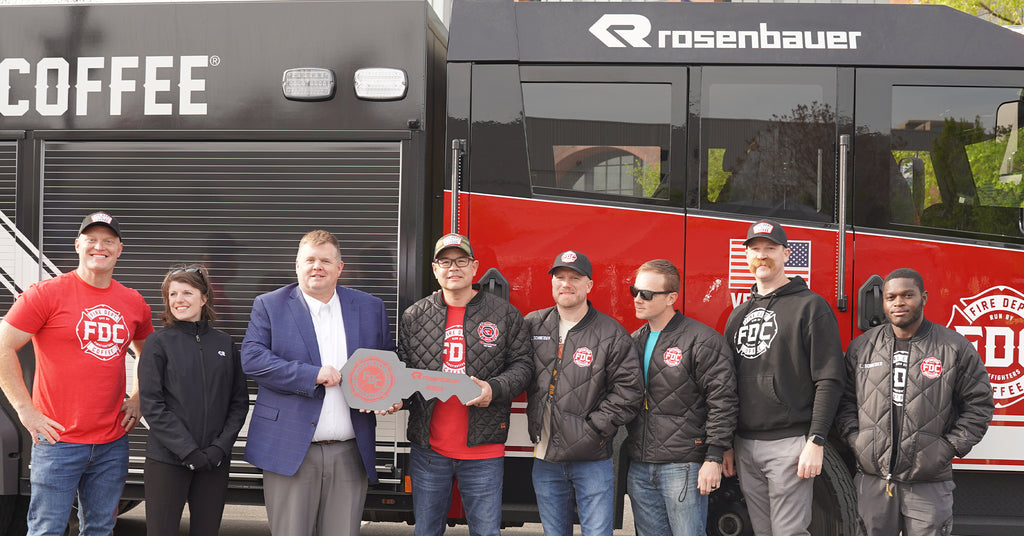 Group photo of team members from Fire Department Coffee and Rosenbauer handing over the key to a new fire truck.