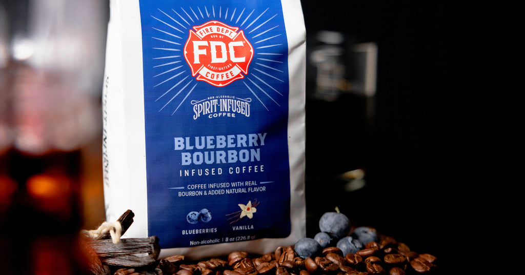 Bag of Blueberry Bourbon Infused Coffee resting on coffee beans with blueberries in front.