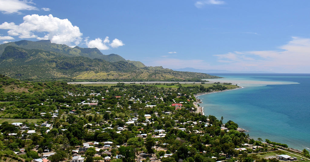 Image of East Timor, Indonesia with a view of the mountains, homes and ocean.