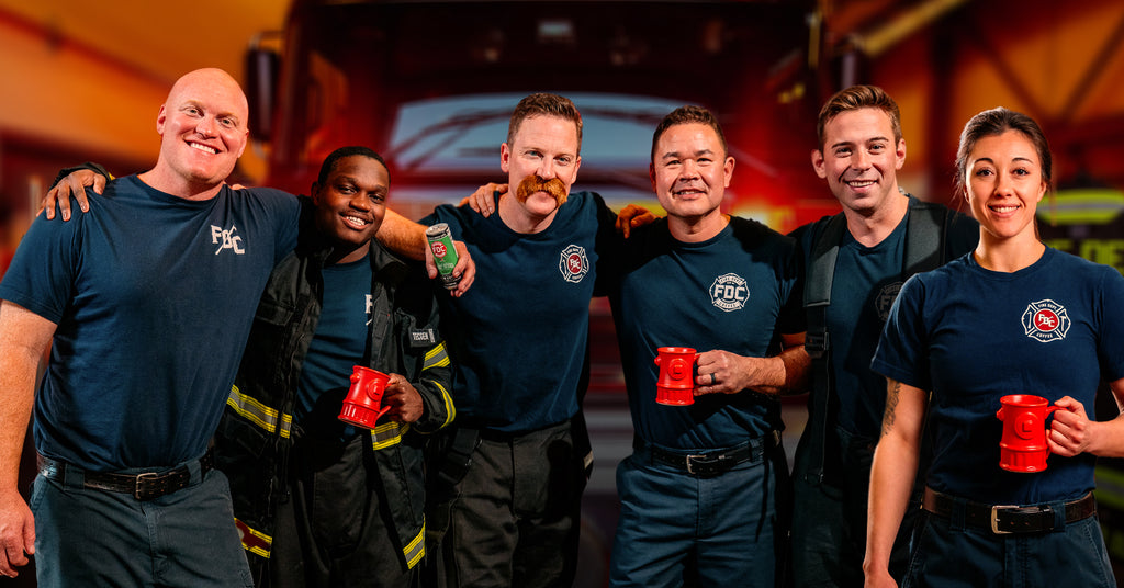 A group of six firefighters standing in front of a fire truck.