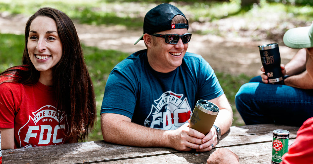 People sitting at a picnic table in warm weather.