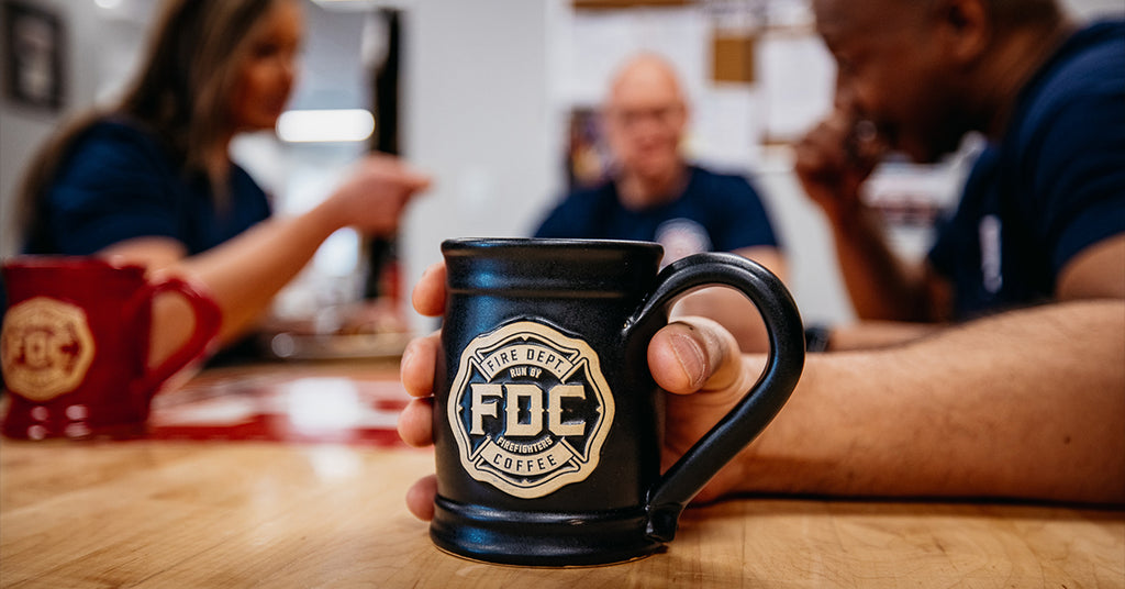 Close up image of a black Fire Dept. Coffee mug on a wood table.