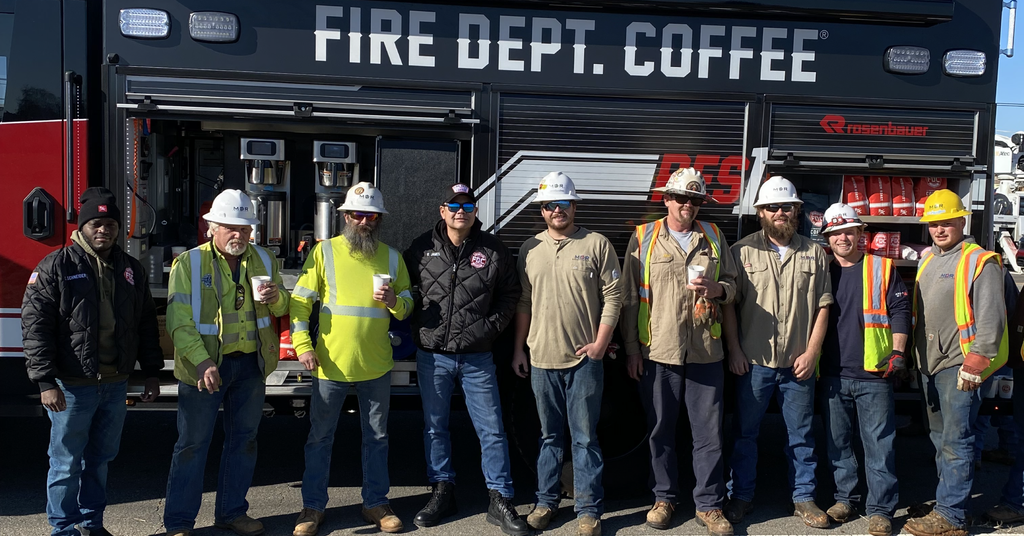 Group of linesmen gathered for a photo with the FDC fire truck in the background providing relief efforts in TN.