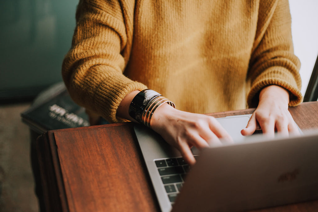 person's arms working at a laptop