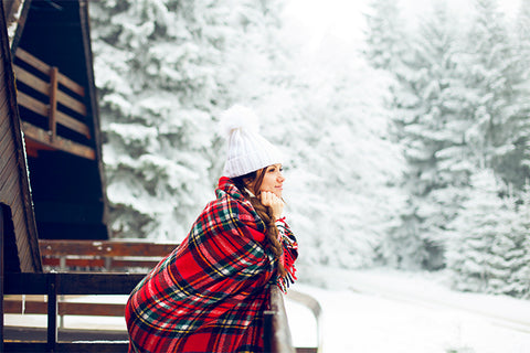 Woman outside in snow wrapped in cozy blanket 