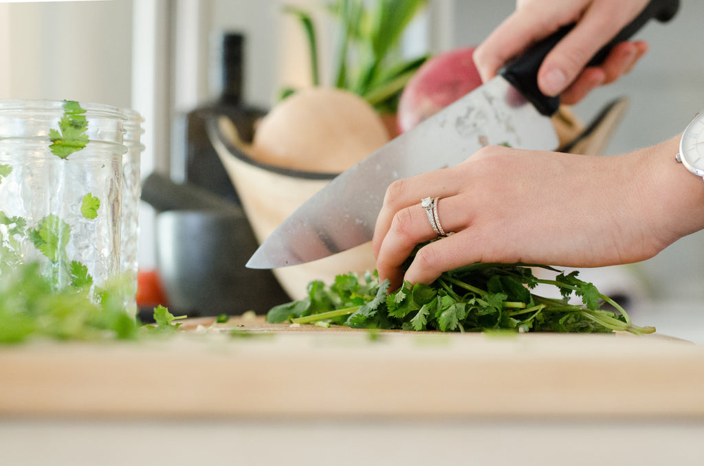hands holding kitchen knife cutting greens 