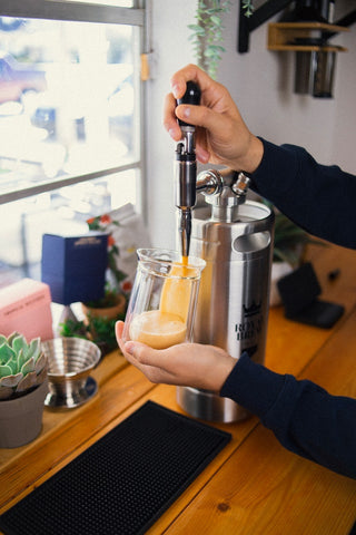 a keg of nitro cold brew coffee being poured