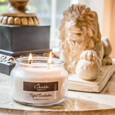 Photo of a two wick burning candle on a table with a small lion statue