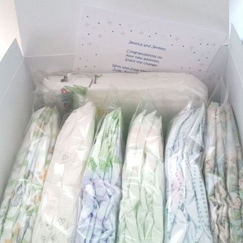 Photo of 7 Diaper Sample Packs in a variety of diaper brands in a white gift box