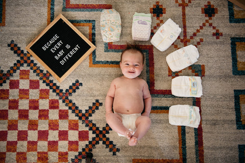 Photo of baby surrounded by diapers with a letterboard "because every baby is different"