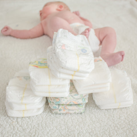 Diaper samples stacked in front of baby