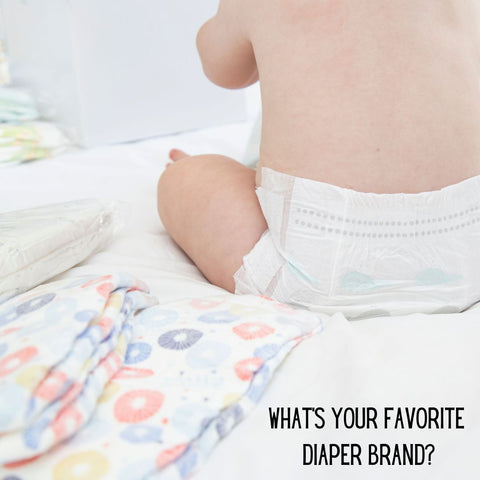 Baby in diaper with a variety of diaper brands next to him