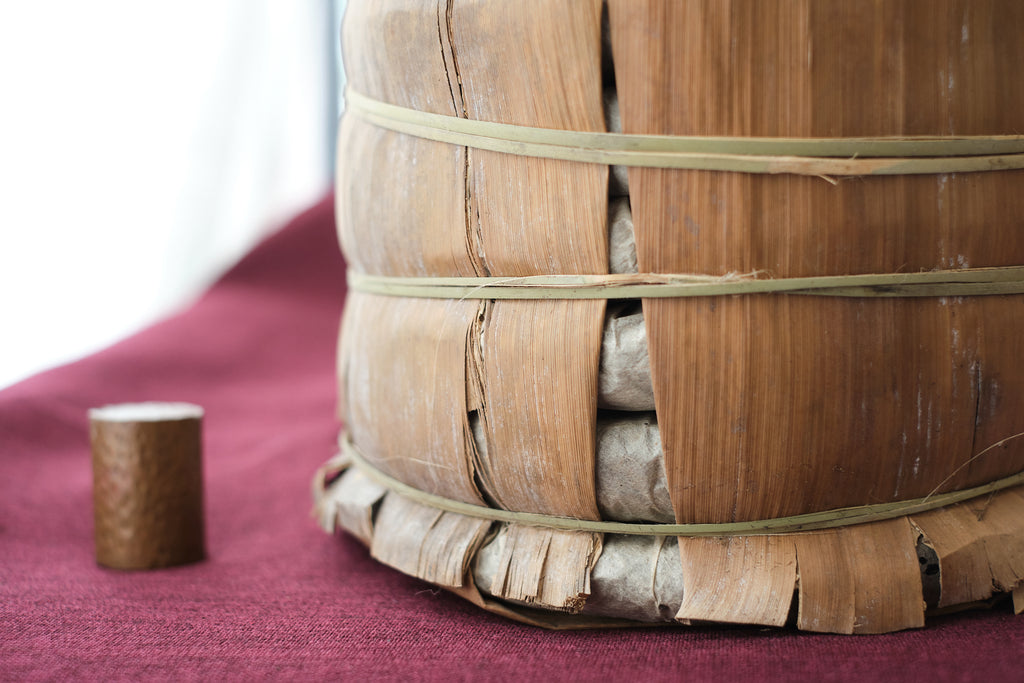 puerh tea cakes wrapped in a bamboo tong