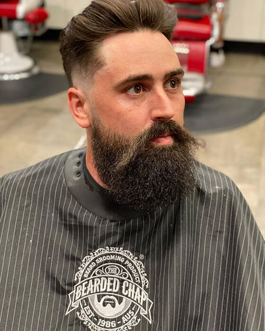 man fade haircut with beard sitting in the bearded chap barbershop
