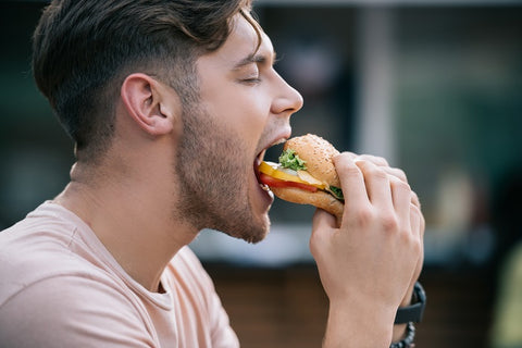 man with a patchy beard eating a junk food
