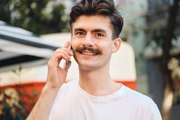 man with moustache talking on the phone