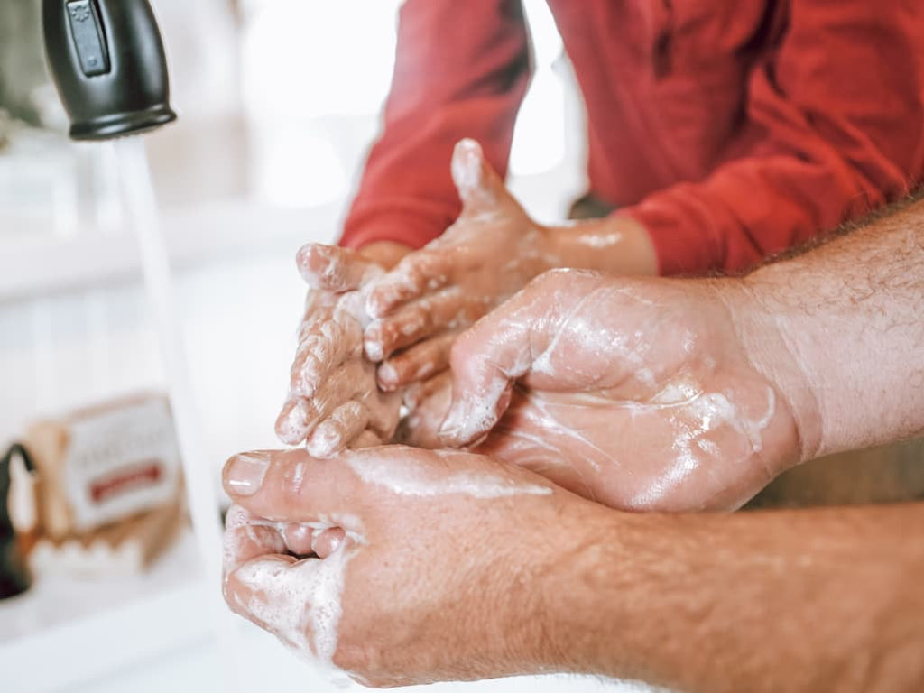 Father and his young son washing hands in sink with goat milk soap