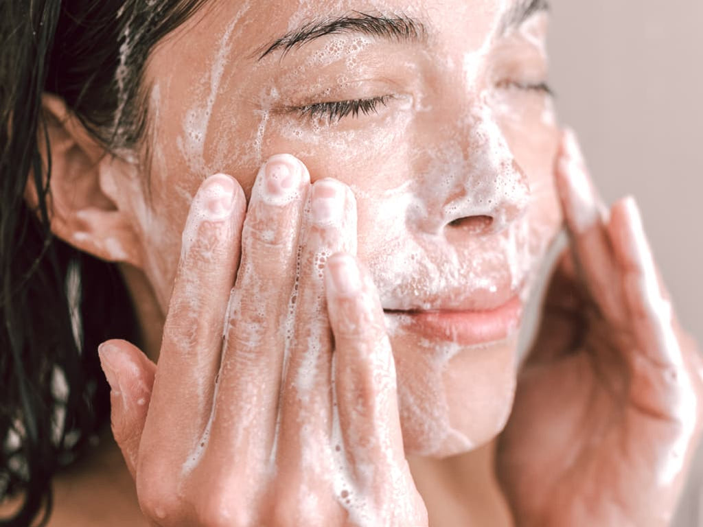 Woman in shower using goat milk soap to exfoliate