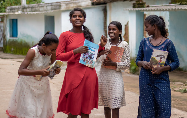 4 young teenage girls of smiling and laughing whilst holding books