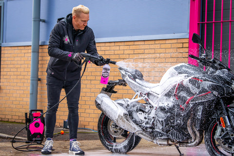Iwan Thomas cleaning a motorcycle with a pressure washer