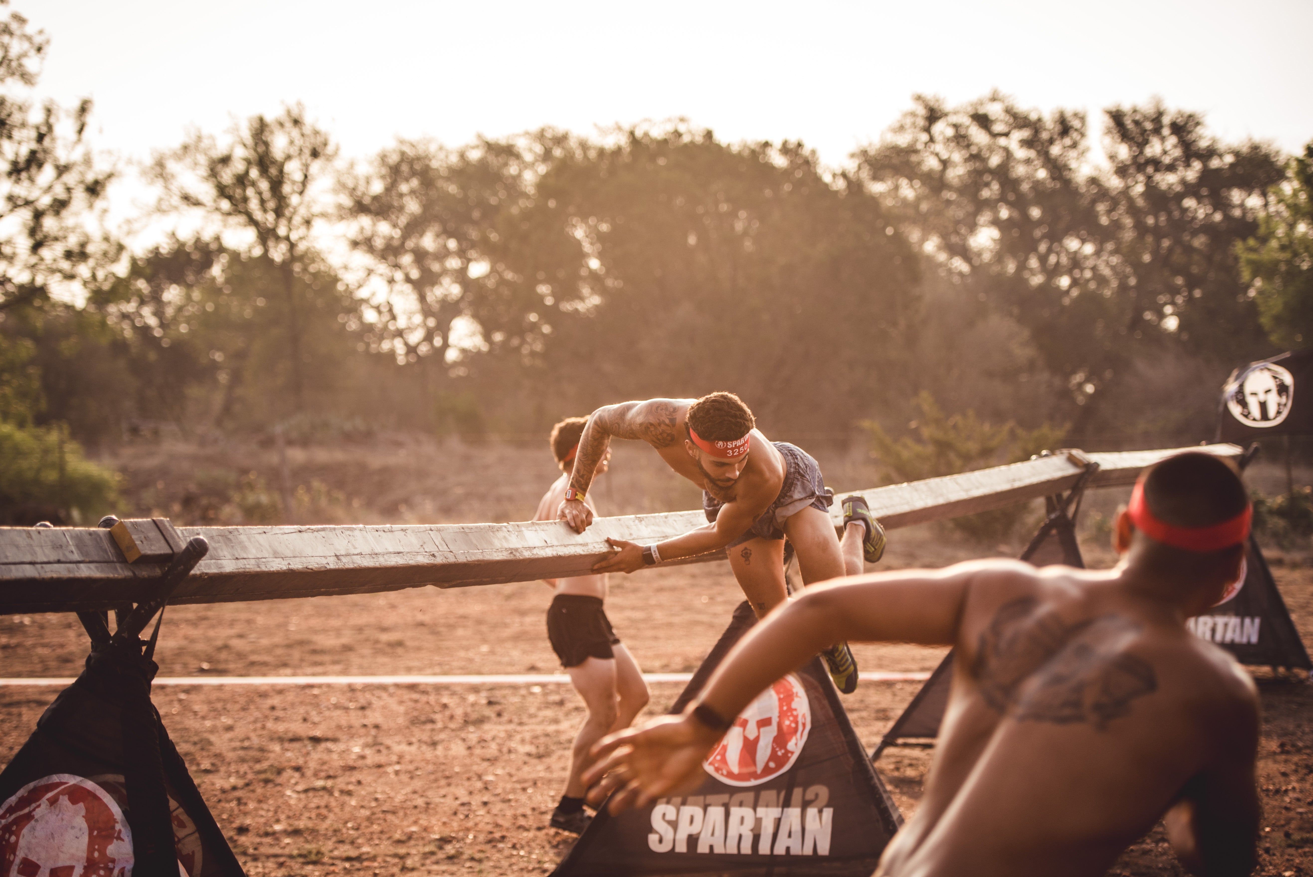 spartan racers jumping over a hurdle during a race