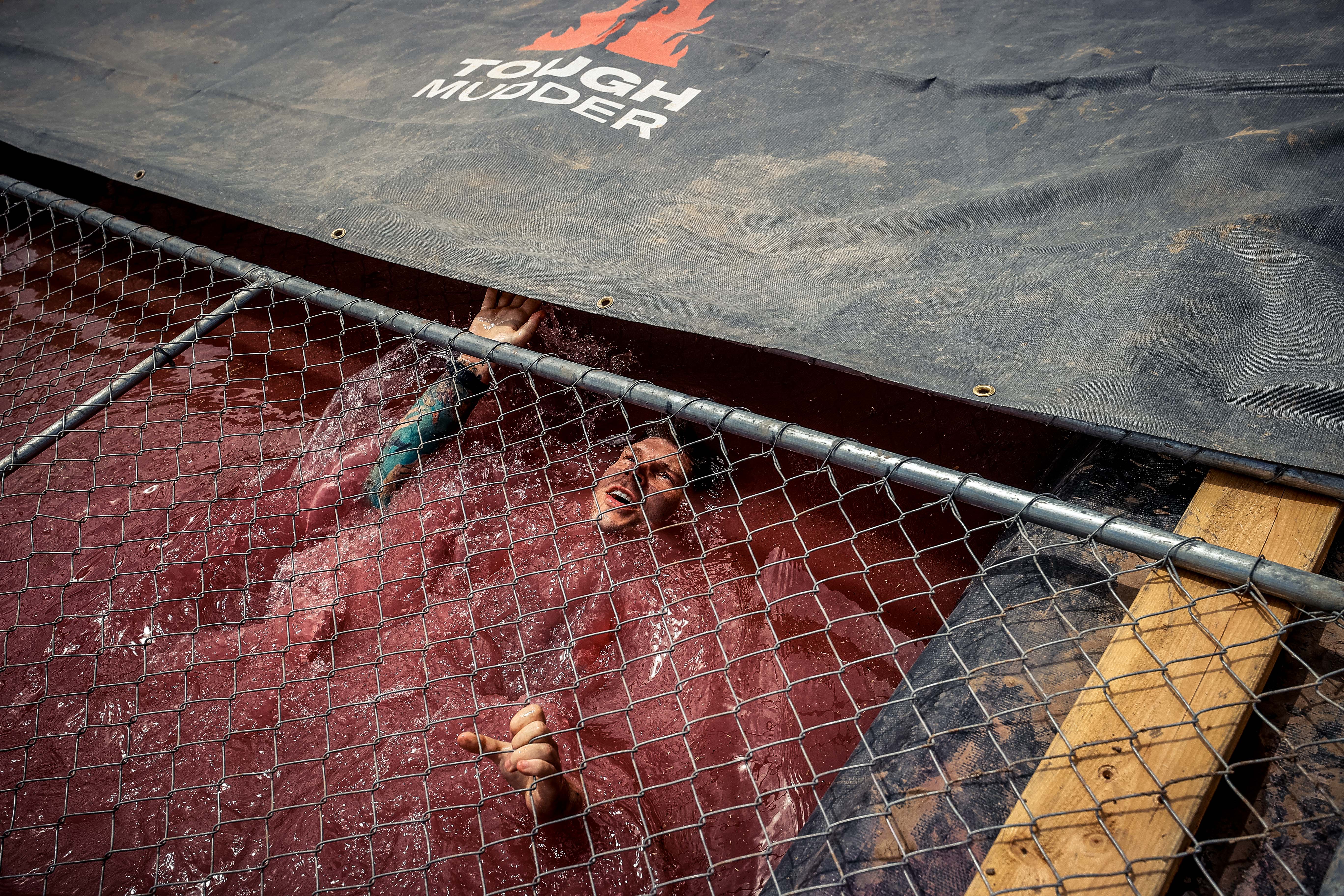 a Tough Mudder racer completing the Cage Crawl obstacle