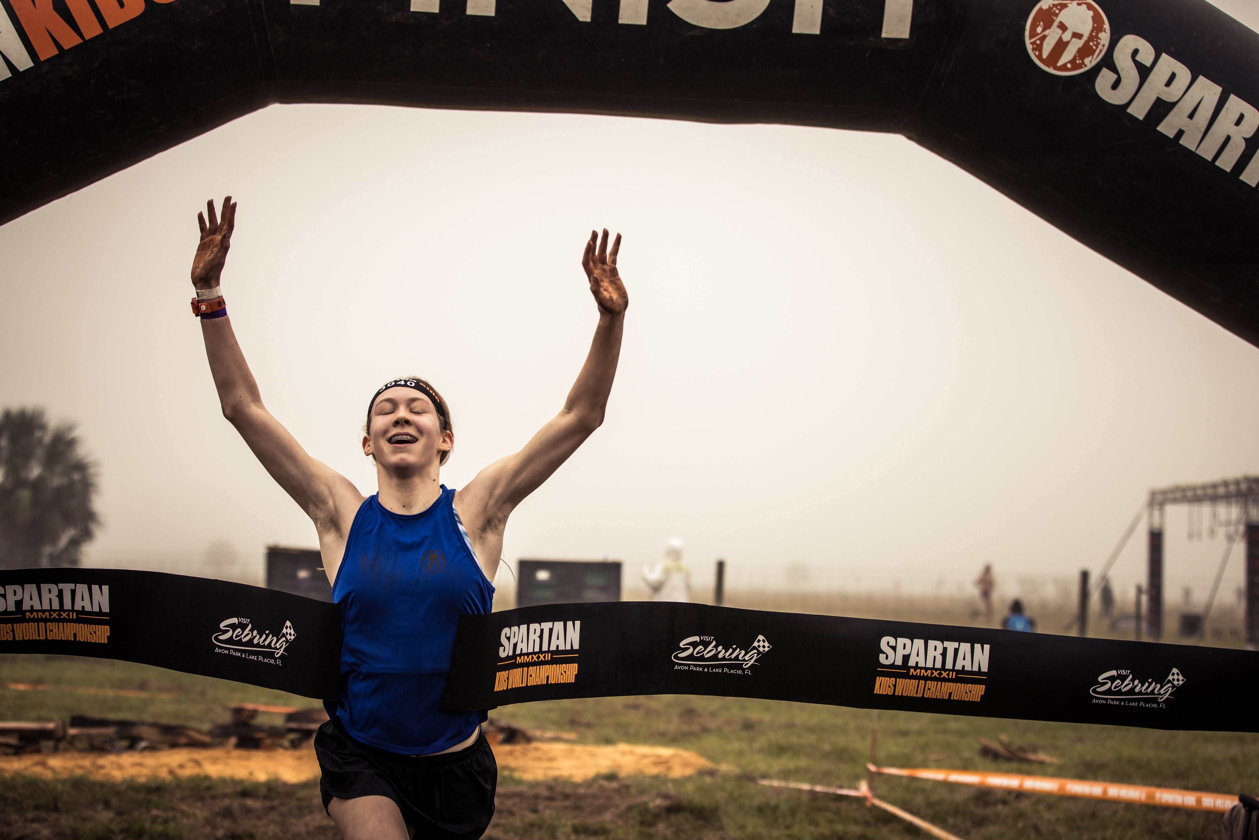 a girl crosses the finish line to win the 2022 Spartan Kids World Championship