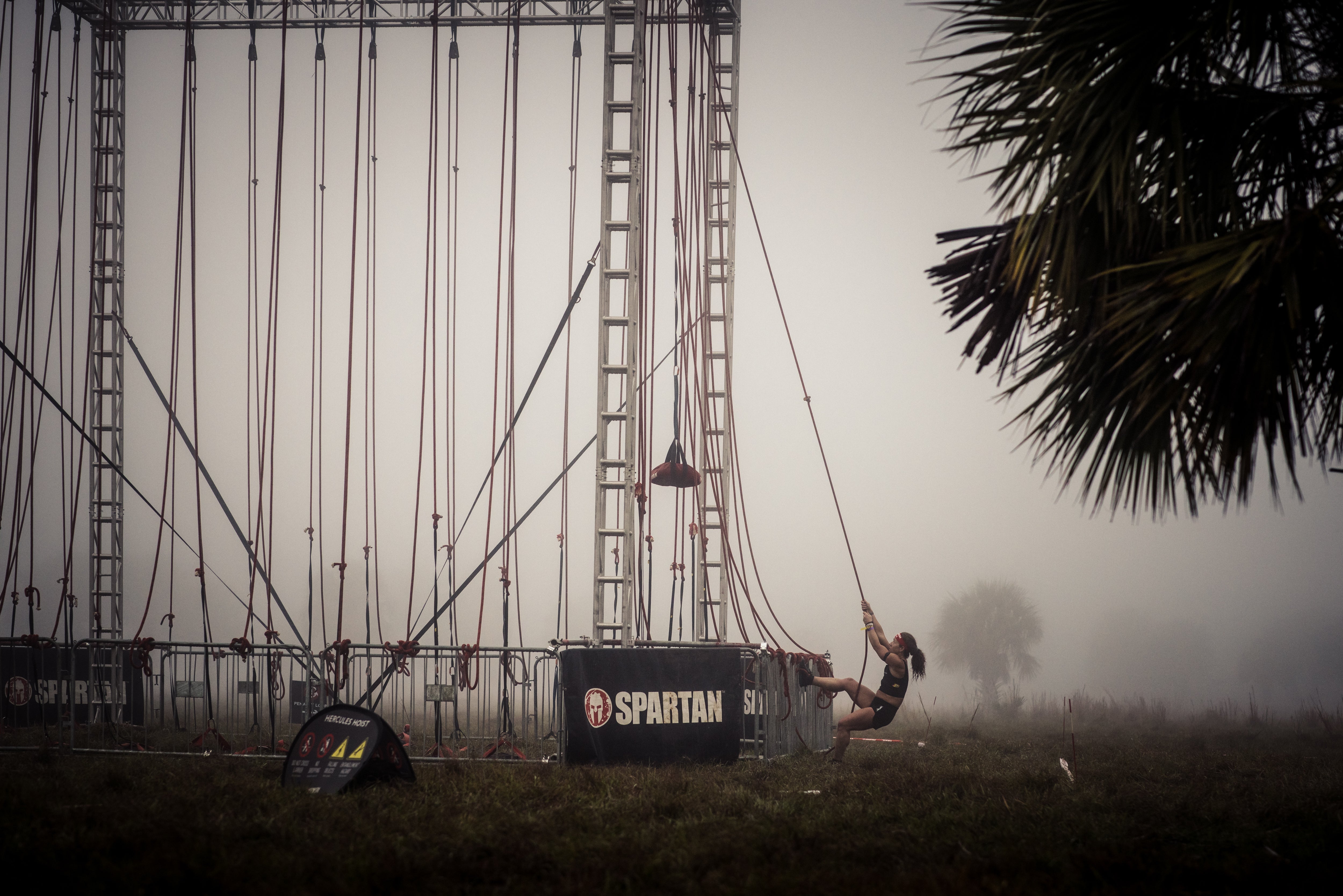 a spartan racer completing the hercules hoist obstacle in the fog