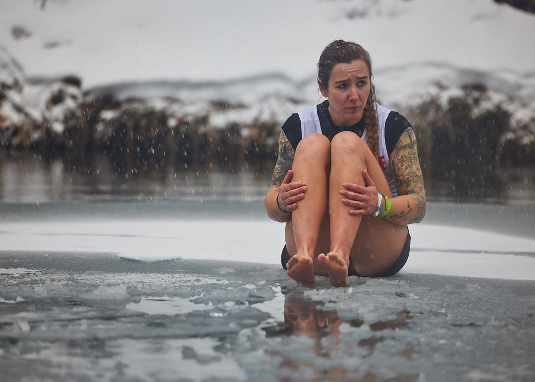 a spartan death racer with no shoes on sitting on a frozen pond