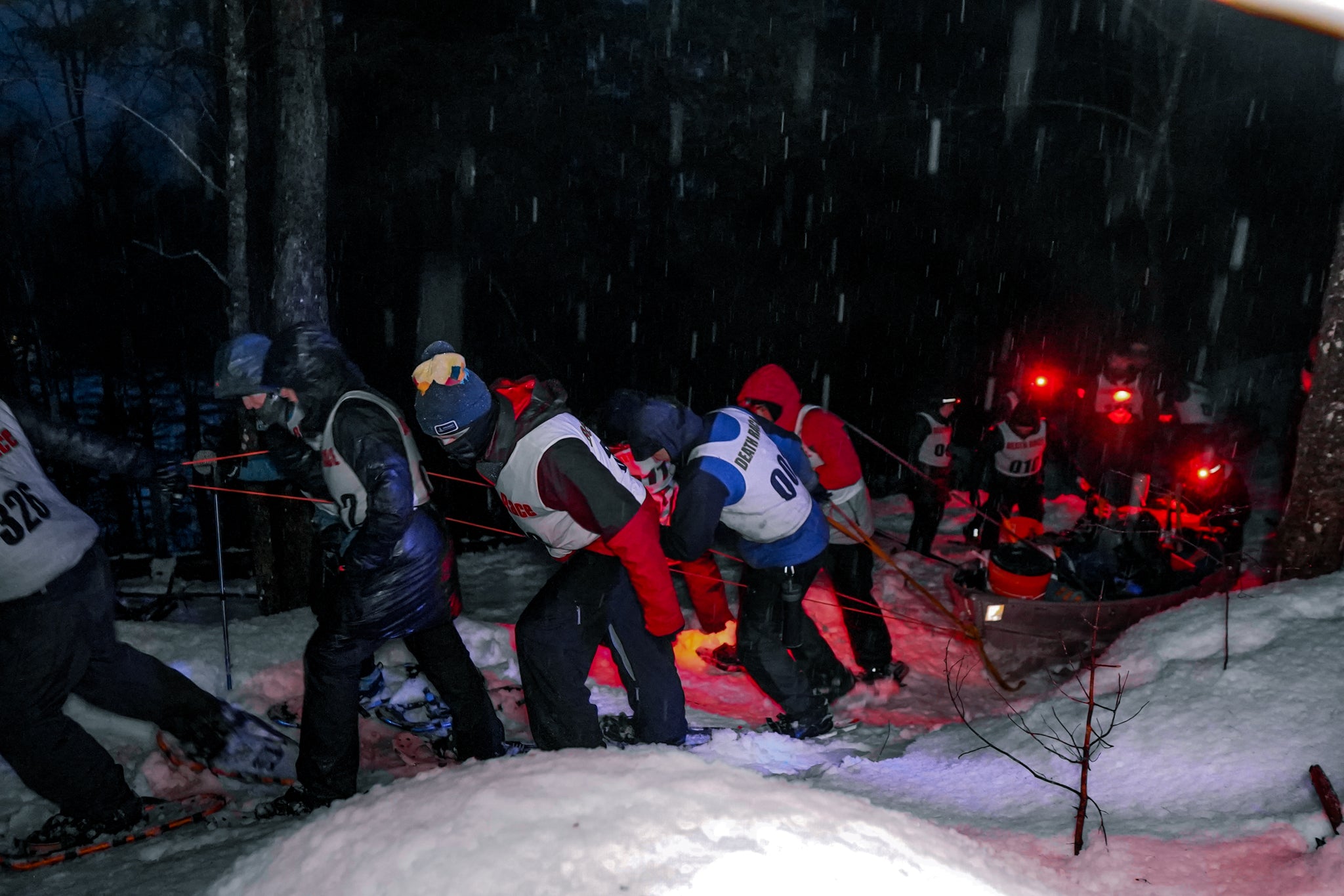 spartan winter death racers pulling cargo up a mountain in the dark and snow
