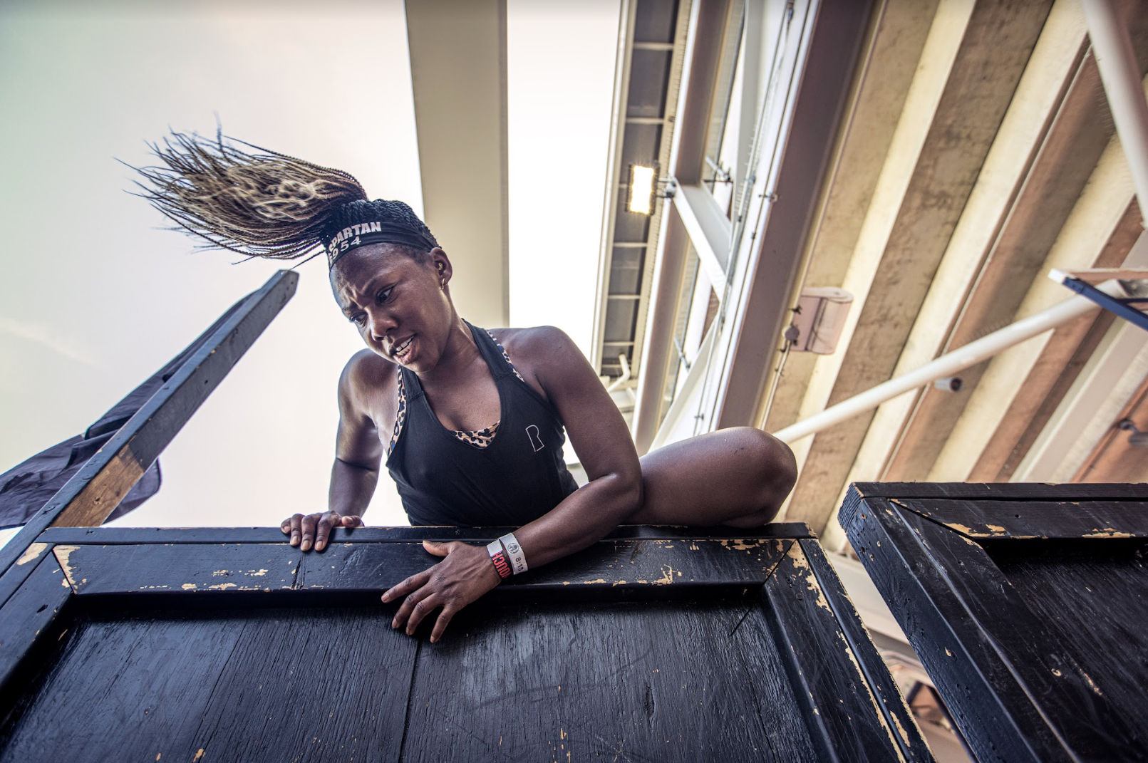 a spartan racer completing a 6-foot wall obstacle at a stadion race