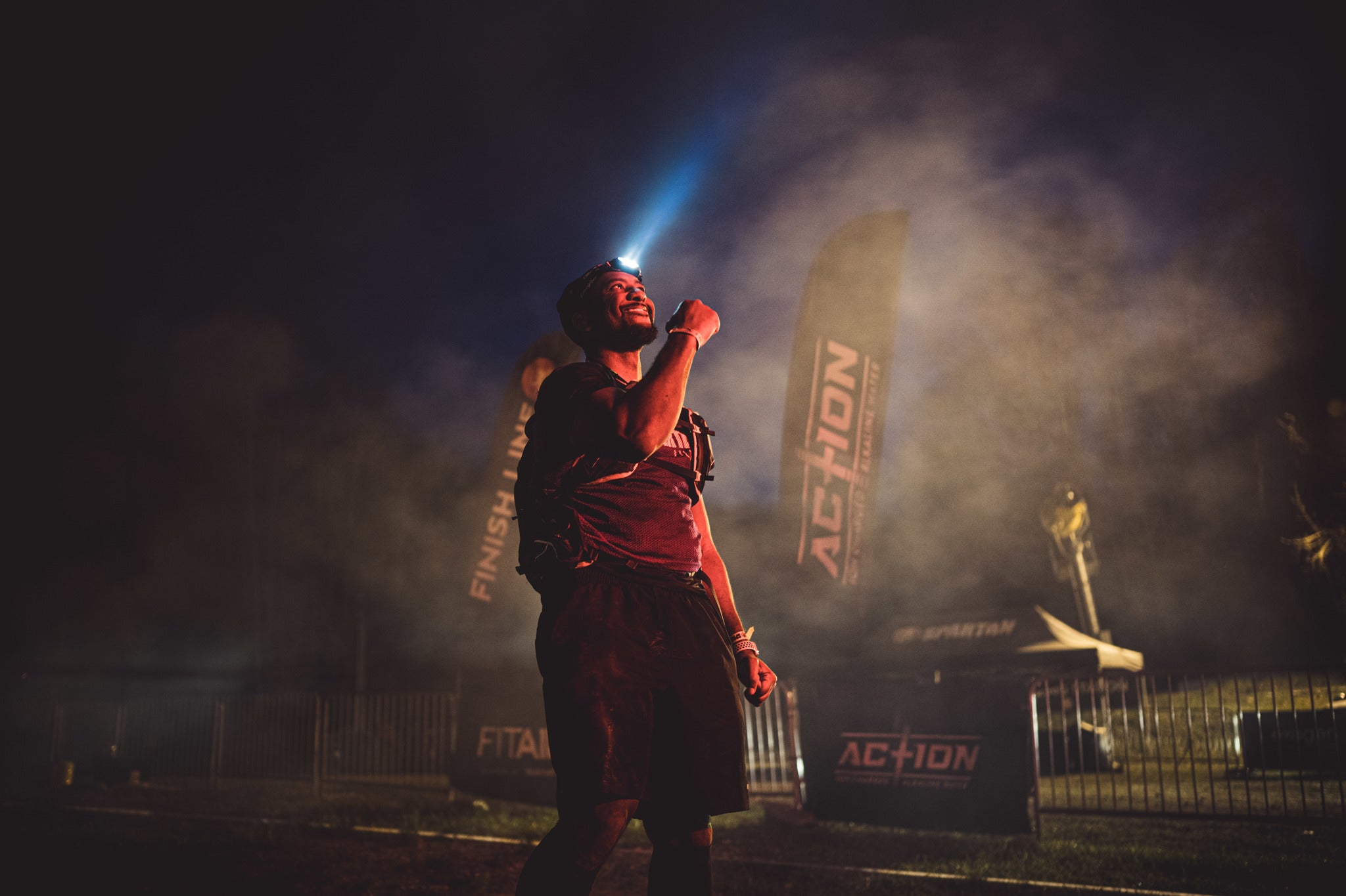 a Spartan racer finishes an Ultra 50K race in the dark wearing a headlamp