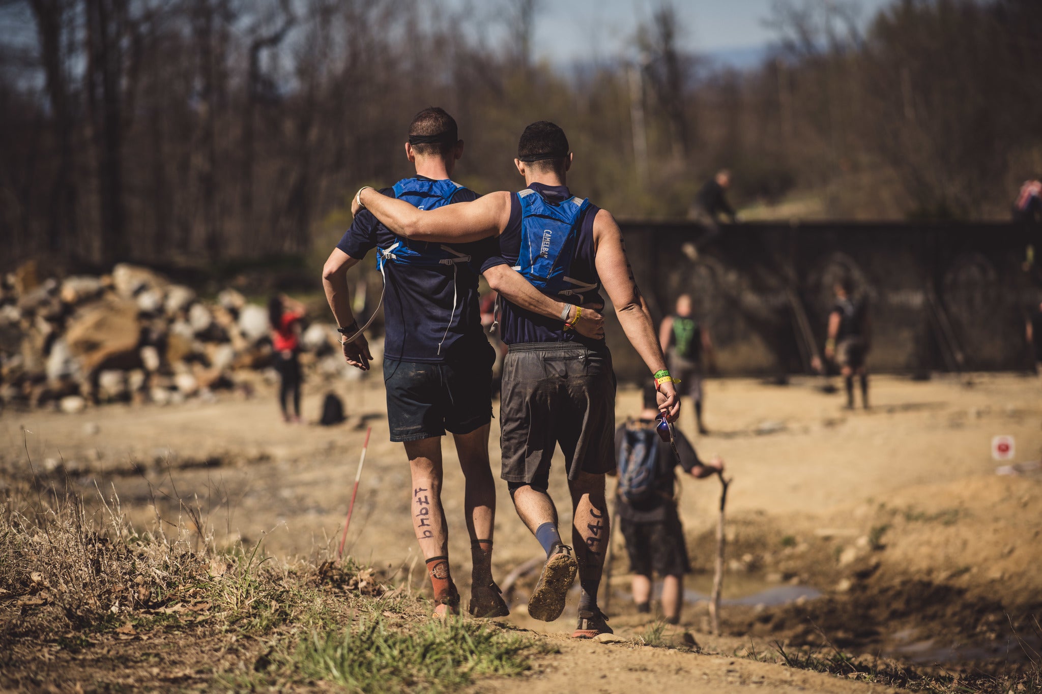 two spartan racers with their arms around one another during a race