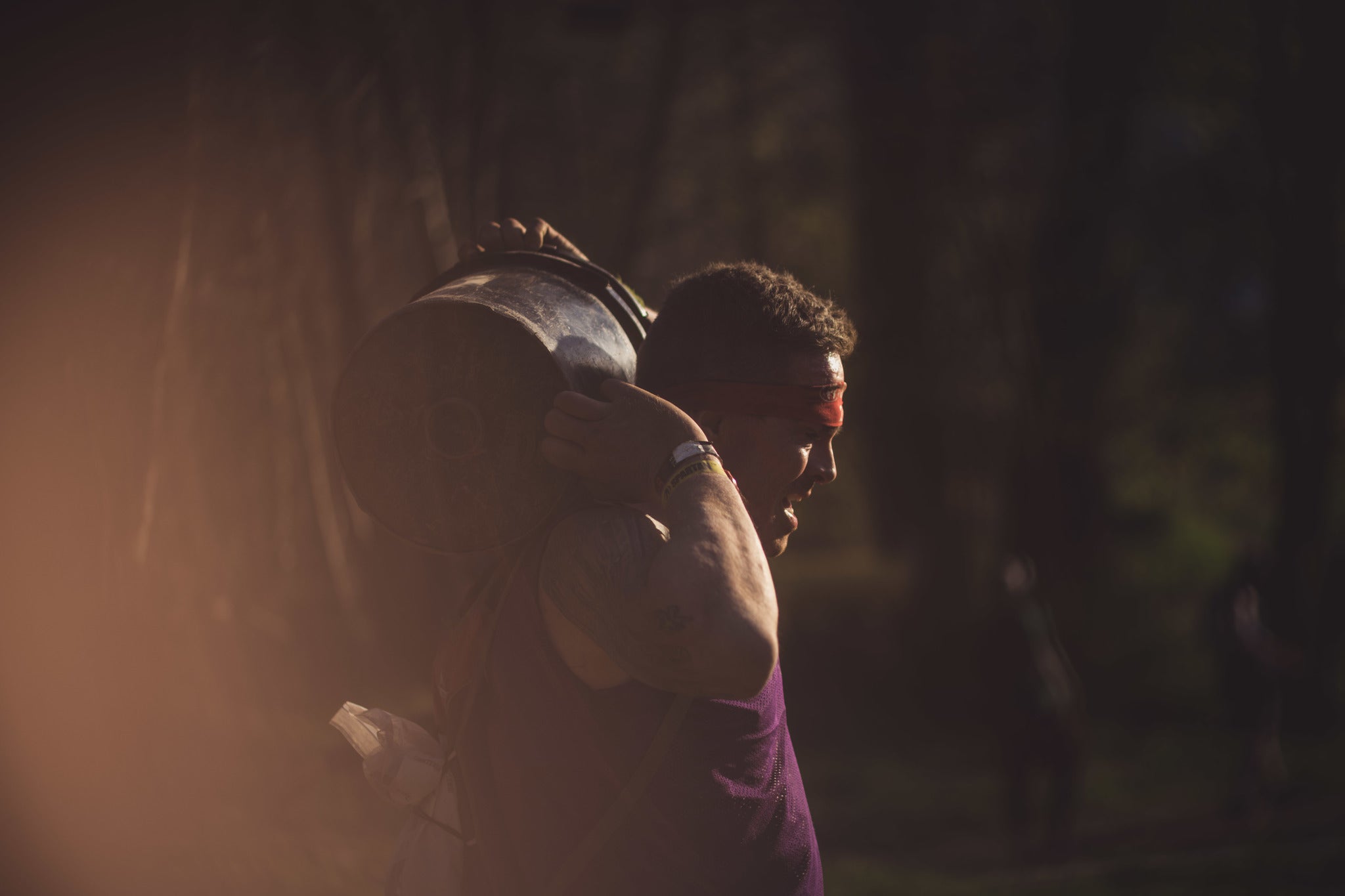 a spartan racer in pain while carrying a bucket during a race