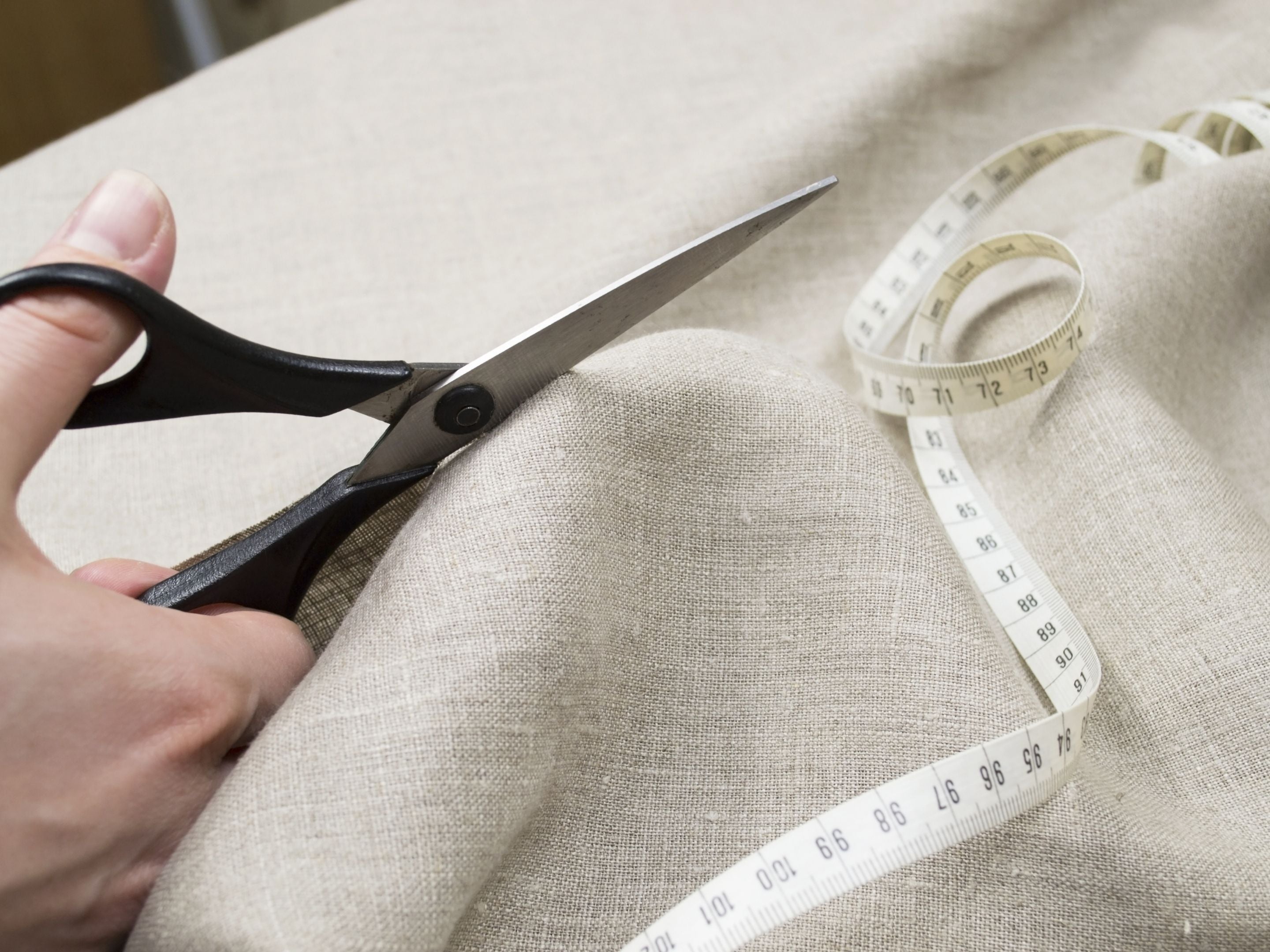 Scissors cutting natural linen fabric