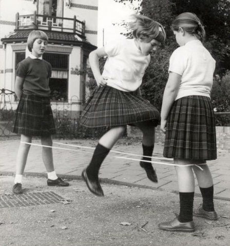 Children playing hopscotch in their tartan school skirts