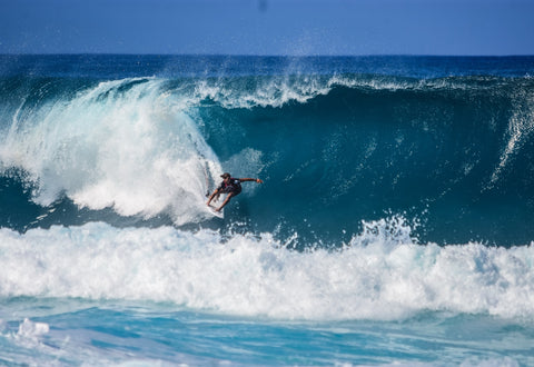 surfer-grabbing-rail-into-barrel-of-blue-overhead-wave-min