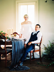 Portrait of a bride and groom at a dining table with candles and a blue velvet runner by The Lesser Bear Florals State and Arrow Planning Auburn and Ivory Photo Henry Photography