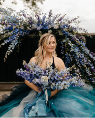 Seated bride in a blue tulle dress with blue flowers and a variety of blue ribbons by The Lesser Bear Florals by Old Slate Farm Photo Taylor Caroline Photo