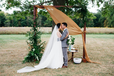 Naturally dyed silk gauze fabric in Pecan Brown, by The Lesser Bear draped over a wedding arbor 