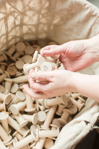 Hands holding wooden spools over a basket of spools by The Lesser Bear, Photo by Starling Studio