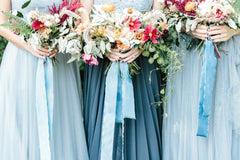 Three bridesmaids holding wedding bouquets with blue ribbon by The Lesser Bear
