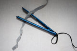 A Lesser Bear silk ribbon running through a hair straightener to remove the wrinkles