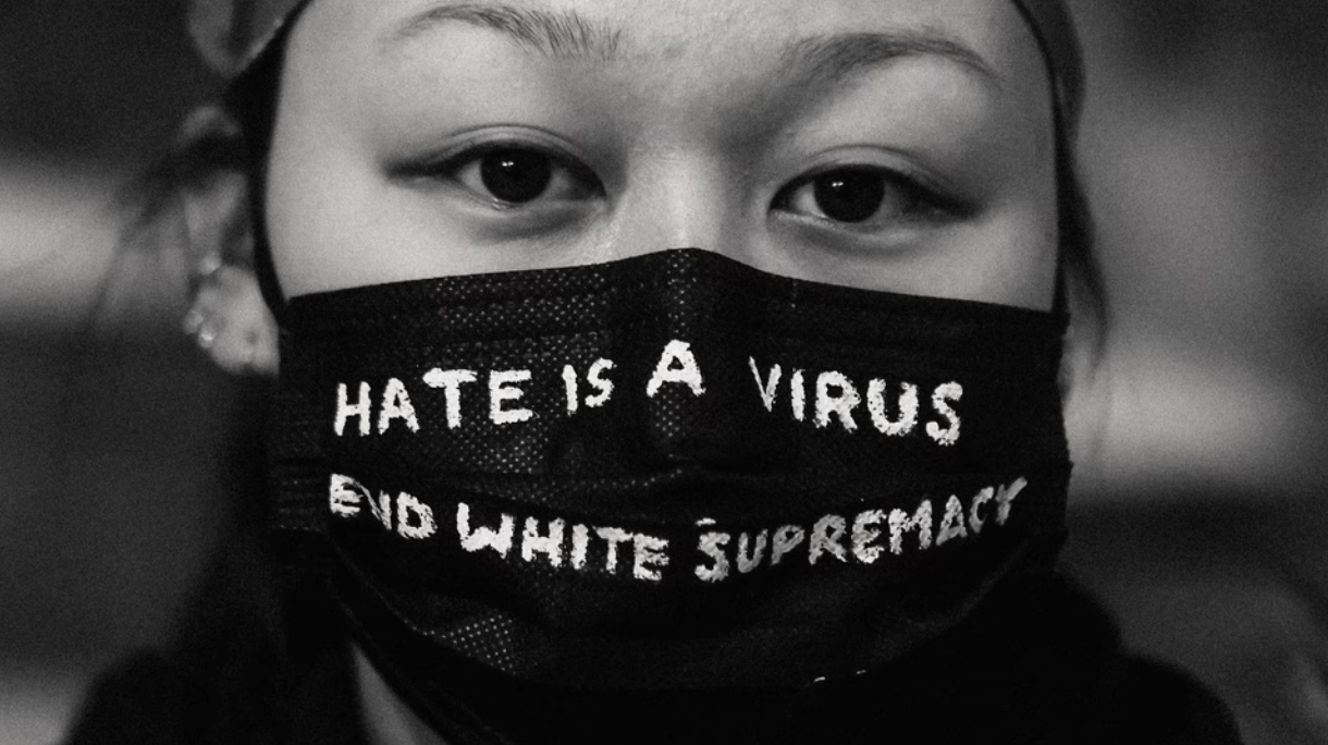 Close up of person wearing a mask that says "Hate is a virus. End white supremacy."