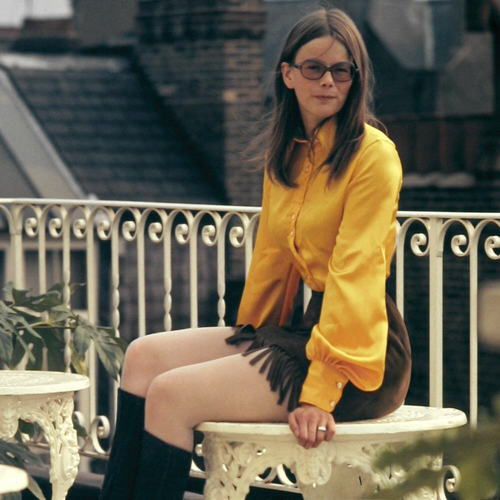 A girl in Kensington, London wearing a mini skirt, bell sleeves and 70's sunglasses