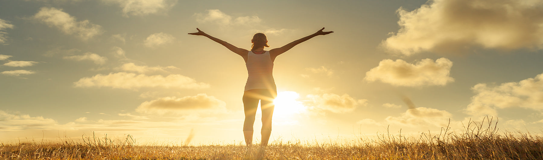 a photo of a woman facing the sun arms extended in gratitude