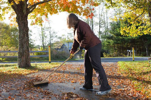 using broom to clean driveway