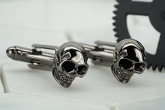 A product image of a pair of vie gunmetal skull cufflinks.