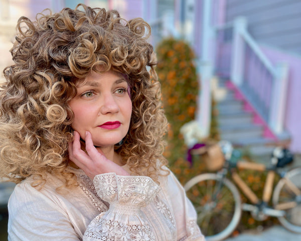 Photo of a person wearing The Hair Helmet, a US CPSC-certified bicycle helmet with a wig-style cover made to look like really big hair, featuring bouncy spiral curls