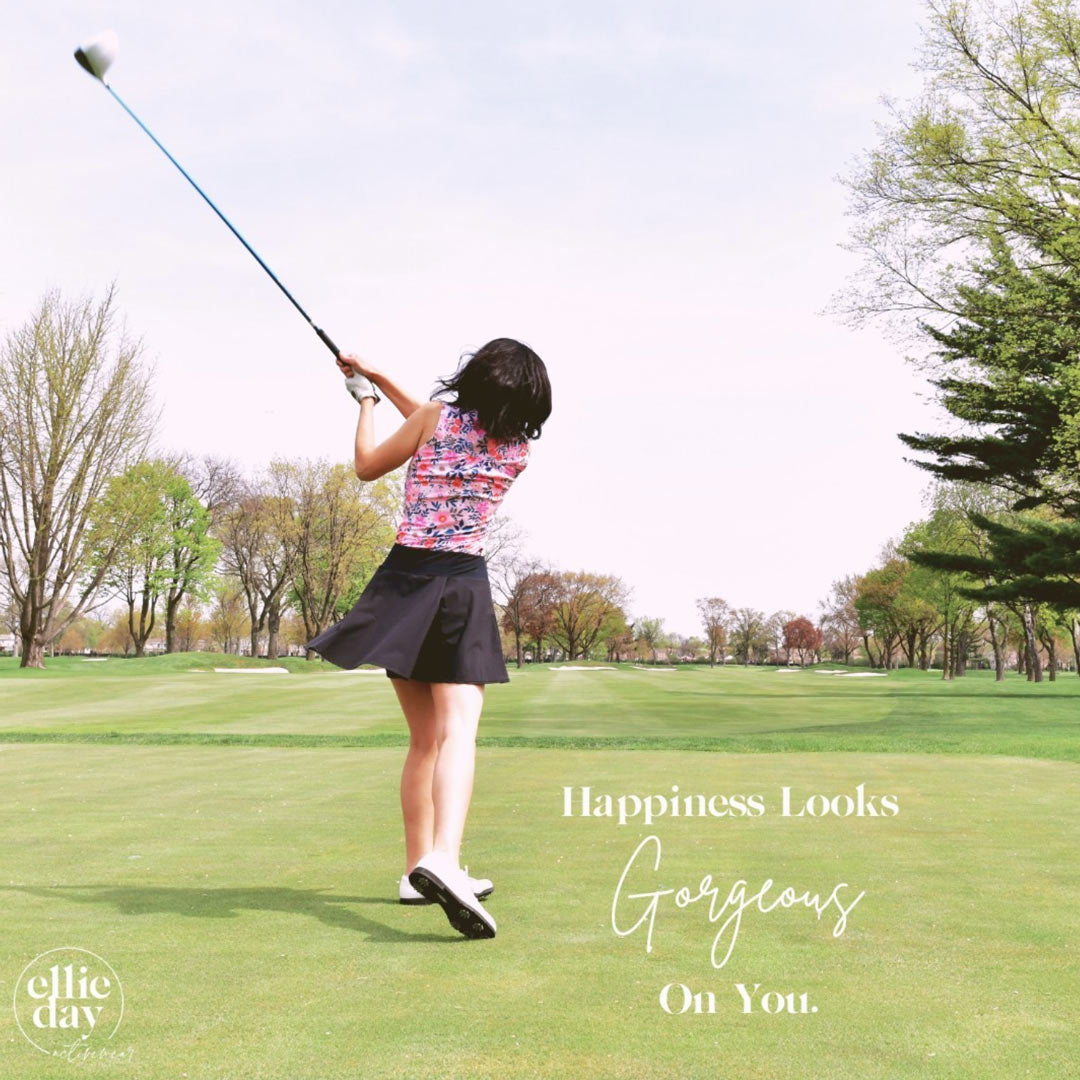 A well dressed woman on a green lawn takes a big swing at a golf ball.